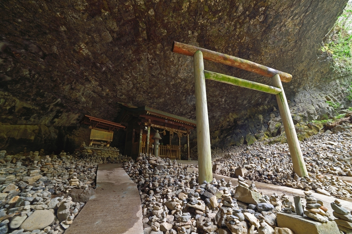 積み石に囲まれた天安河原の社と洞窟内の参拝空間