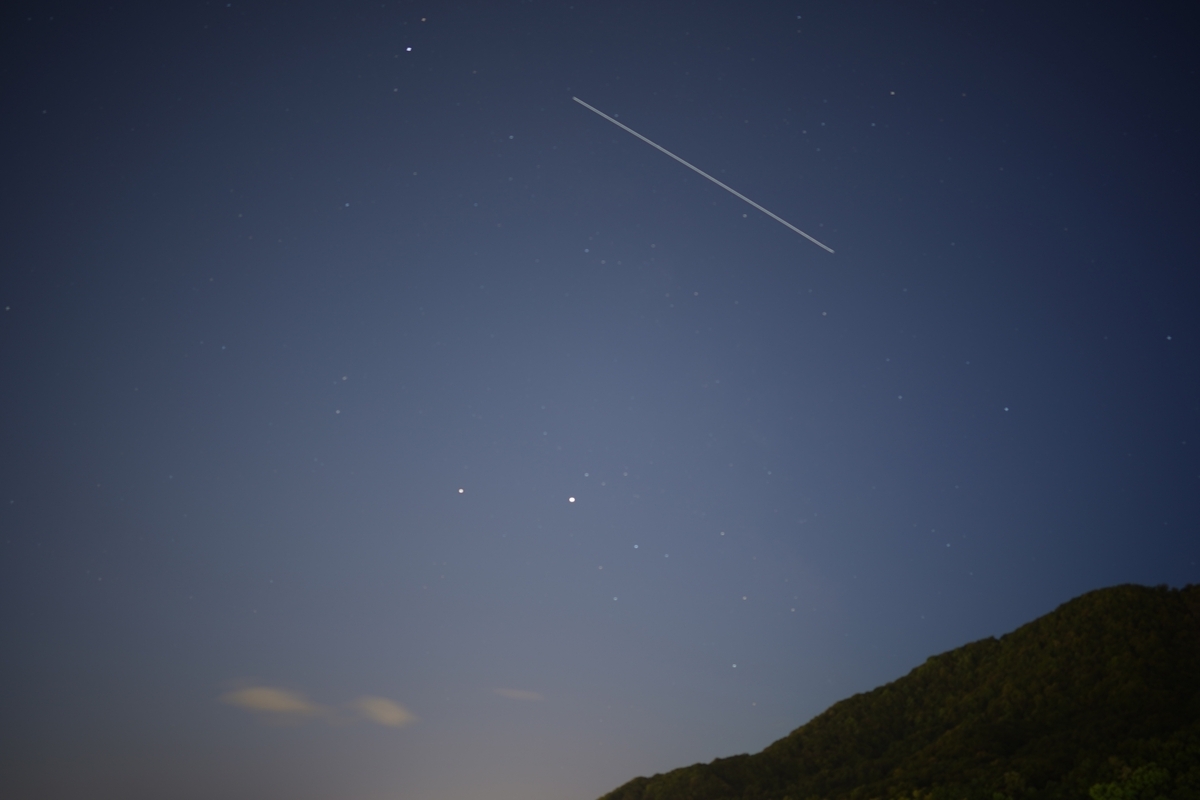 星空に一直線の光跡が伸びる国際宇宙ステーションの通過風景