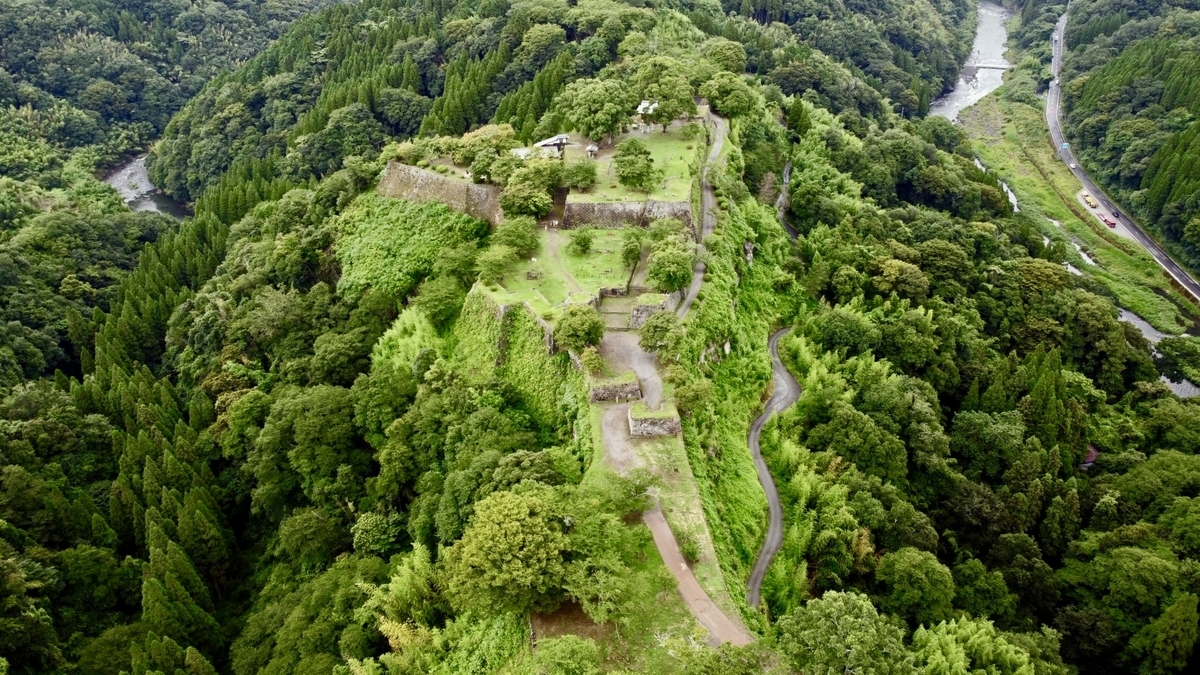 山肌の尾根に広がる岡城跡と石垣を空撮した全景