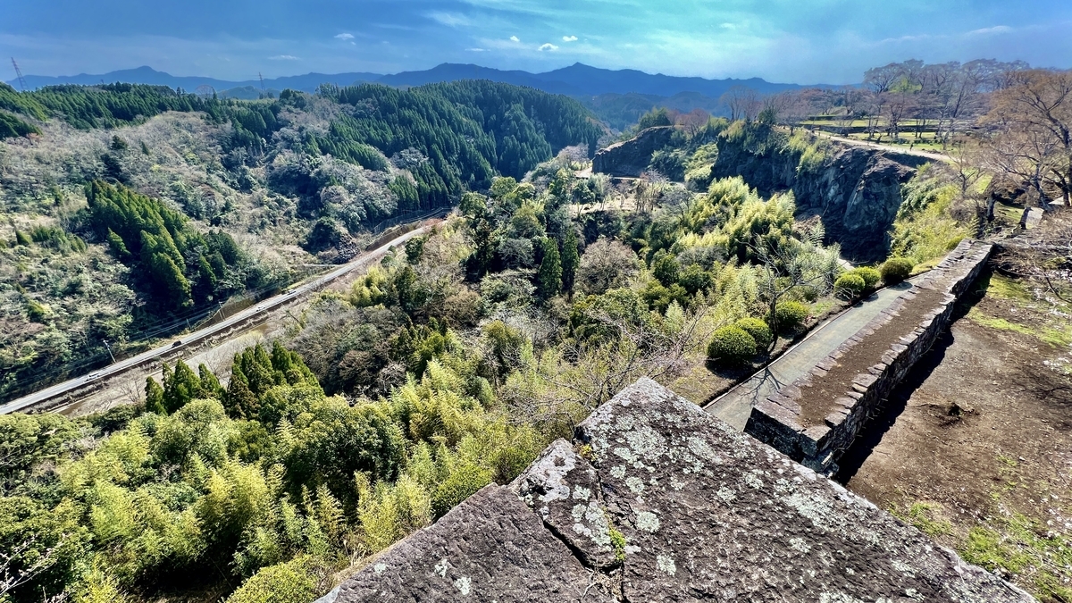 石垣の角から見下ろす渓谷と川沿いの道路