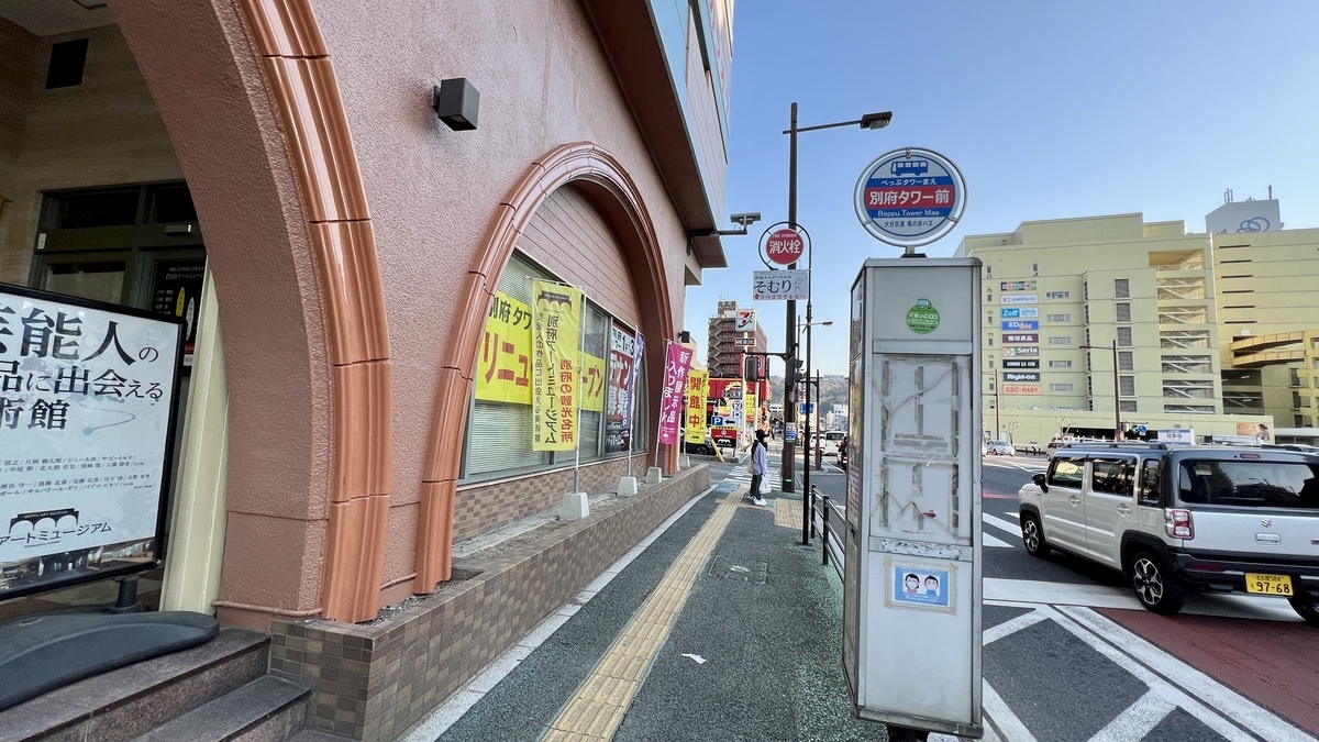 別府タワー前バス停の標識と歩道沿いの街並み