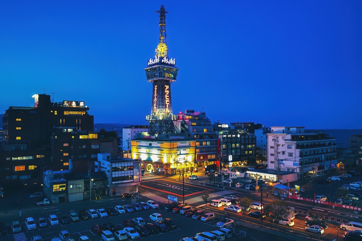 夕暮れの街にライトアップされた別府タワーと周辺の夜景