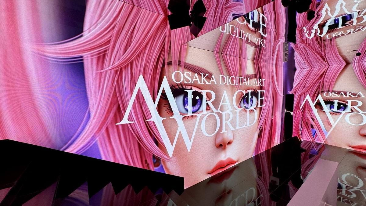 ピンク髪のキャラクターとミラクルワールドのロゴが映る巨大スクリーン