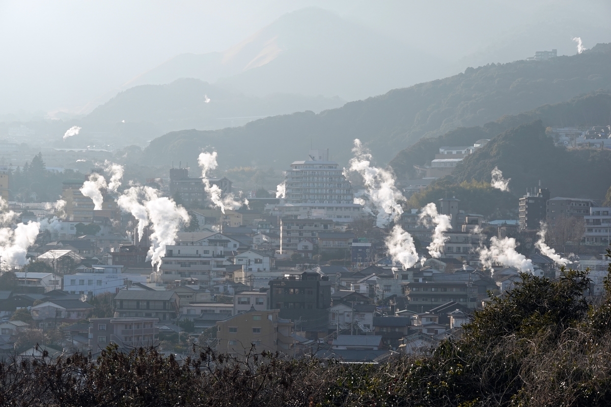 別府の街並みから多数の湯けむりが立ち上り山並みを背景に広がる温泉地の俯瞰風景