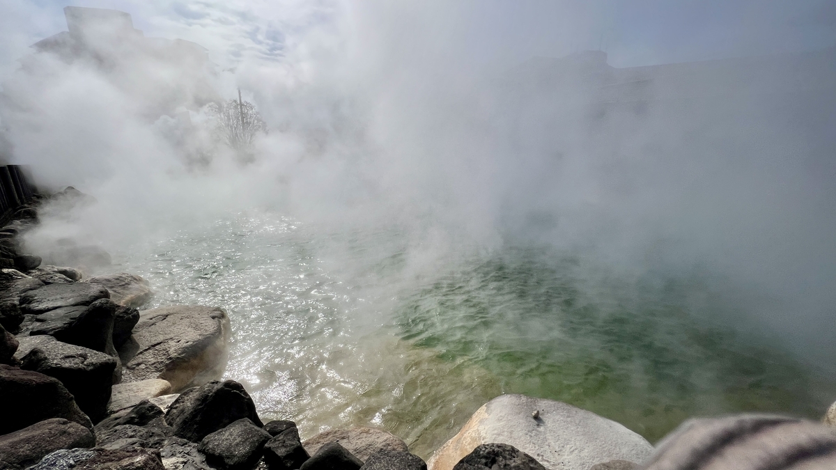 鬼山地獄の噴出で湯気が濃く立ちこめる温泉池と岩場の迫力ある景色