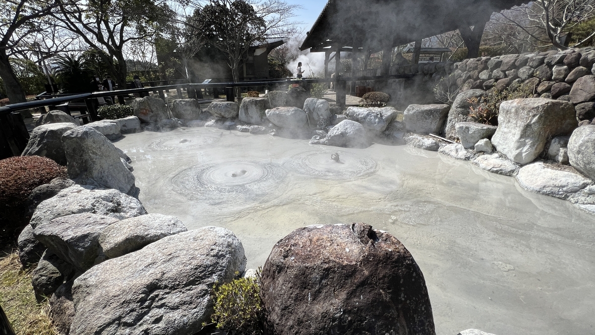鬼石坊主地獄の灰色の熱泥がぐつぐつ湧く池と石で囲まれた観覧エリア