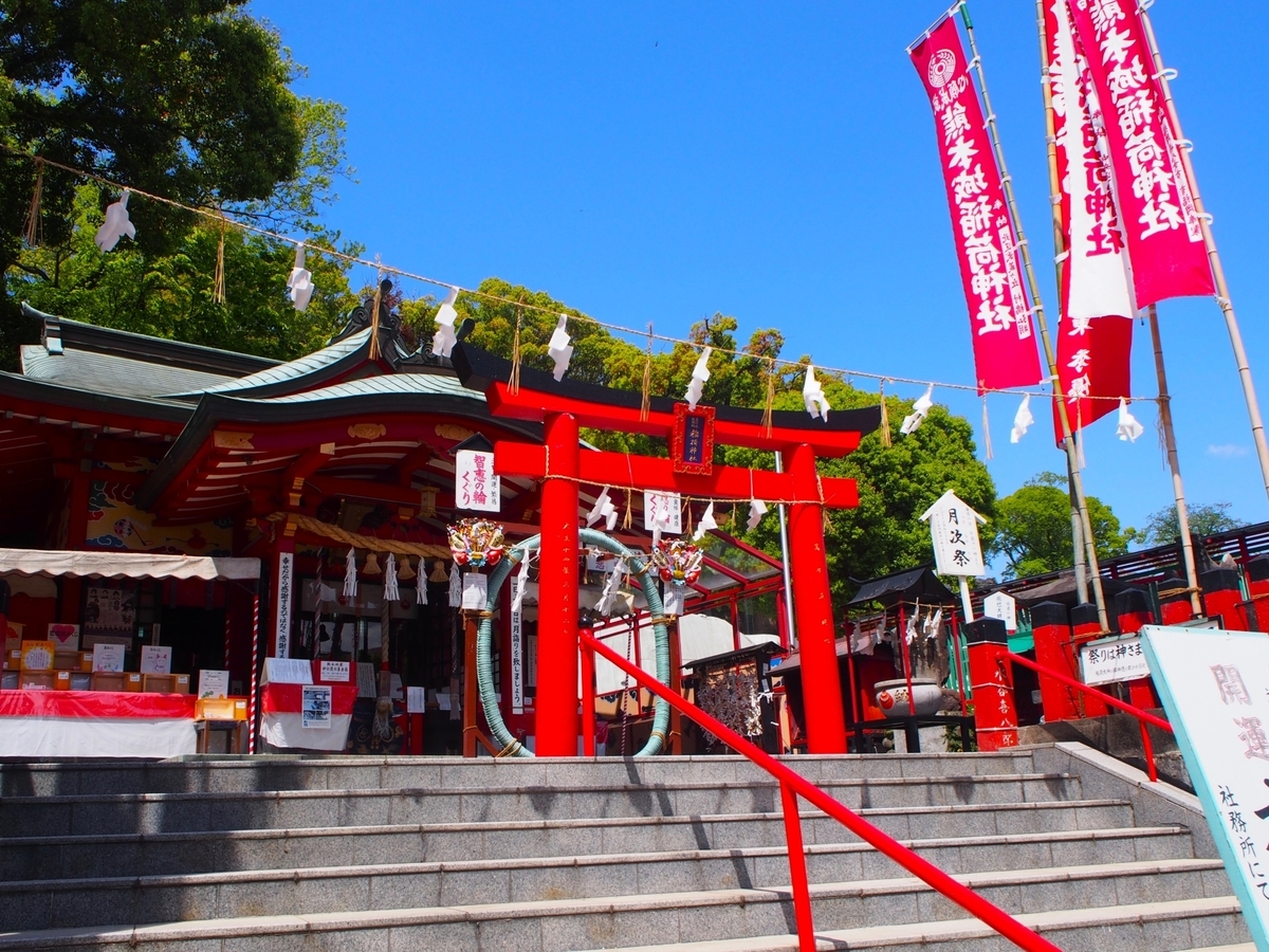 青空の下で石段上に並ぶ朱色の鳥居と本殿