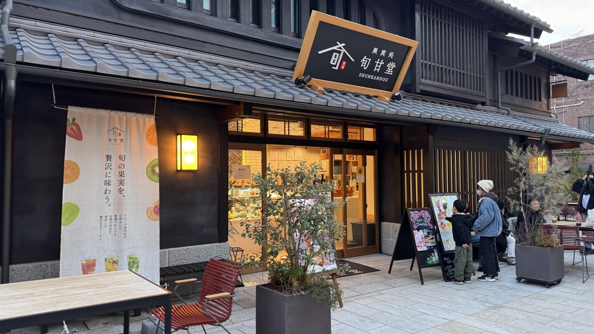 果実処 旬甘堂の店頭 旬の果実スイーツの看板と試飲メニューを見上げる親子連れ