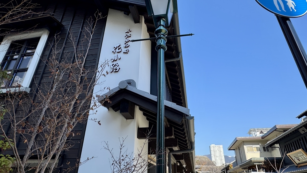 白壁の町屋に掲げられた小江戸甲府花小路の縦看板 青空に街灯と瓦屋根が映える眺め