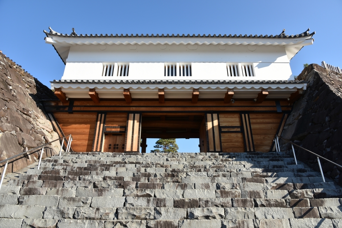 石段の上に建つ白壁の鉄門を正面から見上げた構図