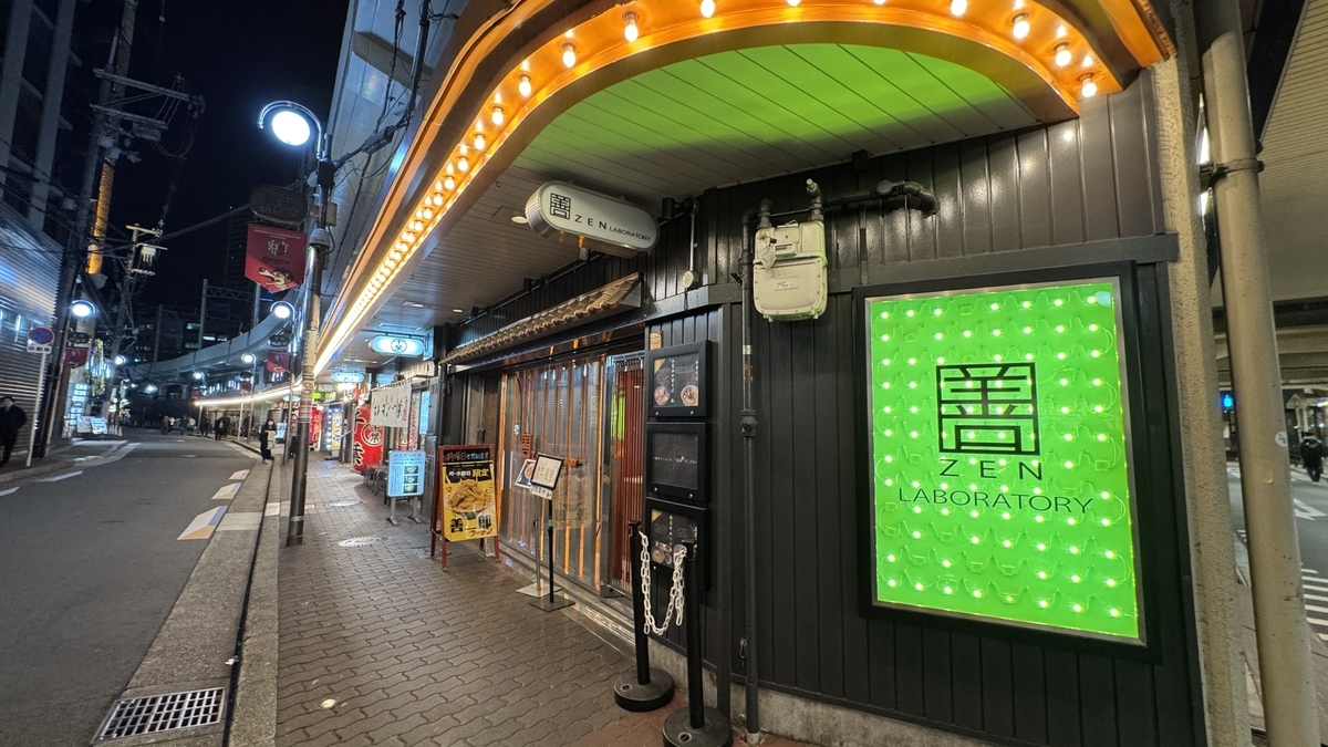 夜の芝田商店街に並ぶ店舗の看板とネオンが灯る通り