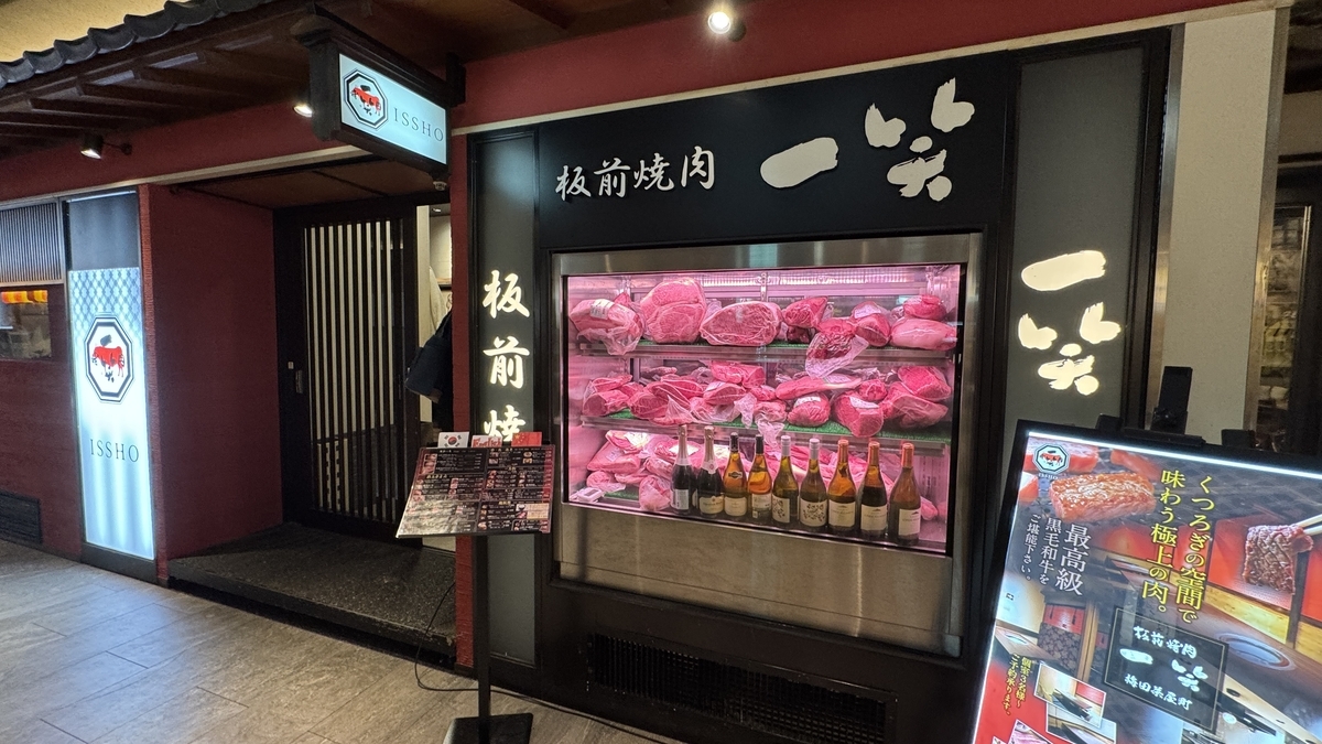 板前焼肉一笑の店頭に並ぶ和牛の肉ケースと日本酒のボトル