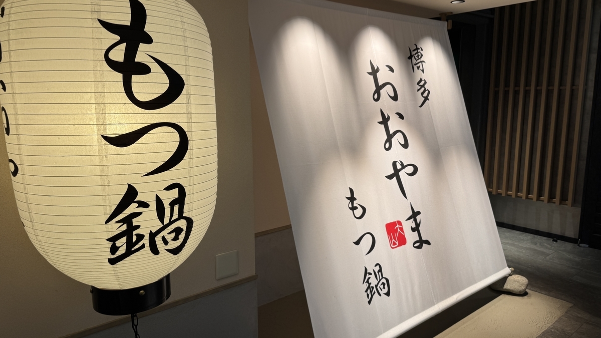 博多おおやまもつ鍋の入口に掲げられた白いのれんと提灯