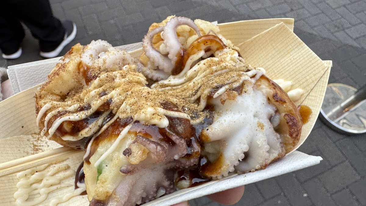 イイダコが丸ごと入ったたこ焼きにソースとマヨネーズをかけた持ち帰りの一皿