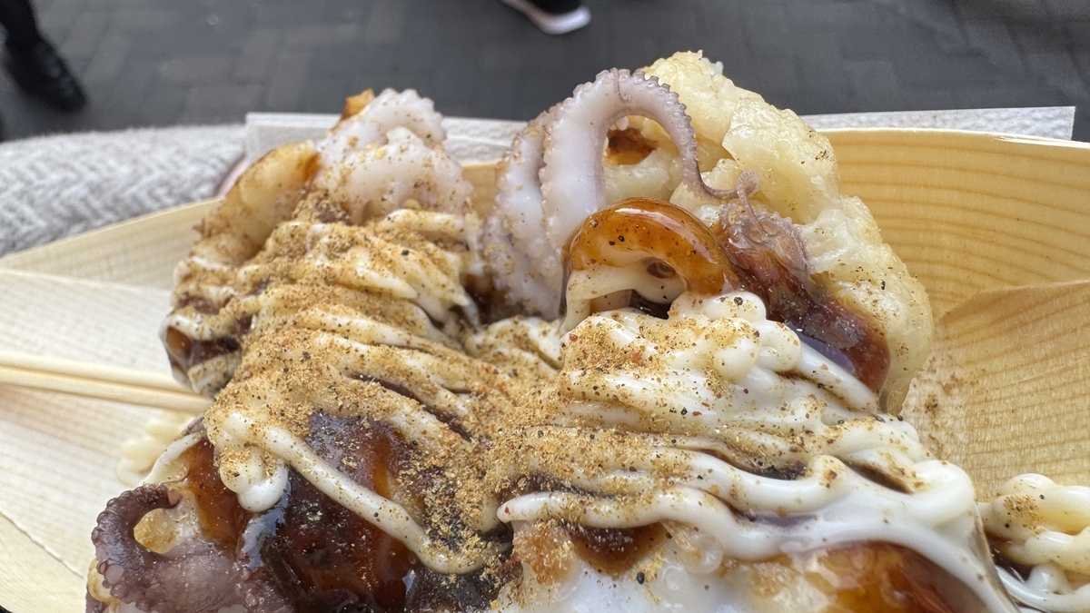 イイダコの足がはみ出したたこ焼き3個にソースとマヨネーズをかけた木皿