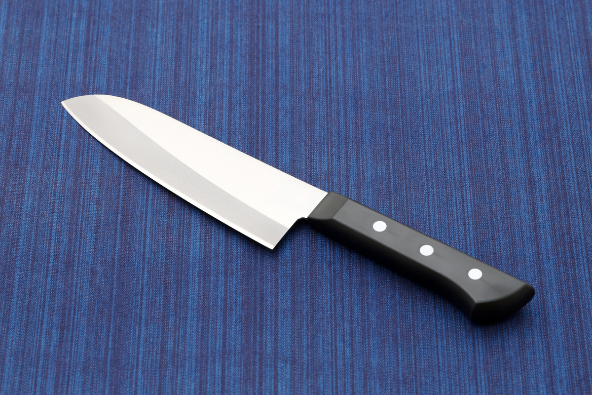 青い布の上に置かれた三徳包丁の刃先と黒いハンドル