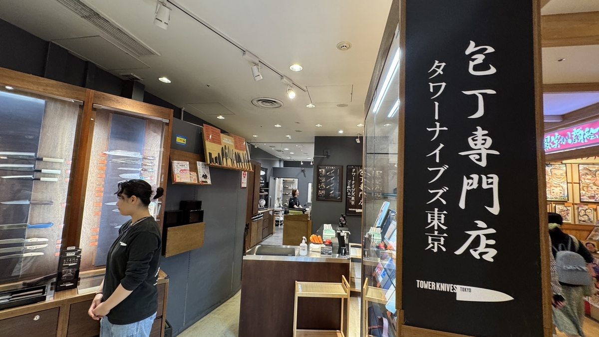 タワーナイブズ東京の店内入口と包丁が並ぶディスプレイ棚を案内するスタッフ
