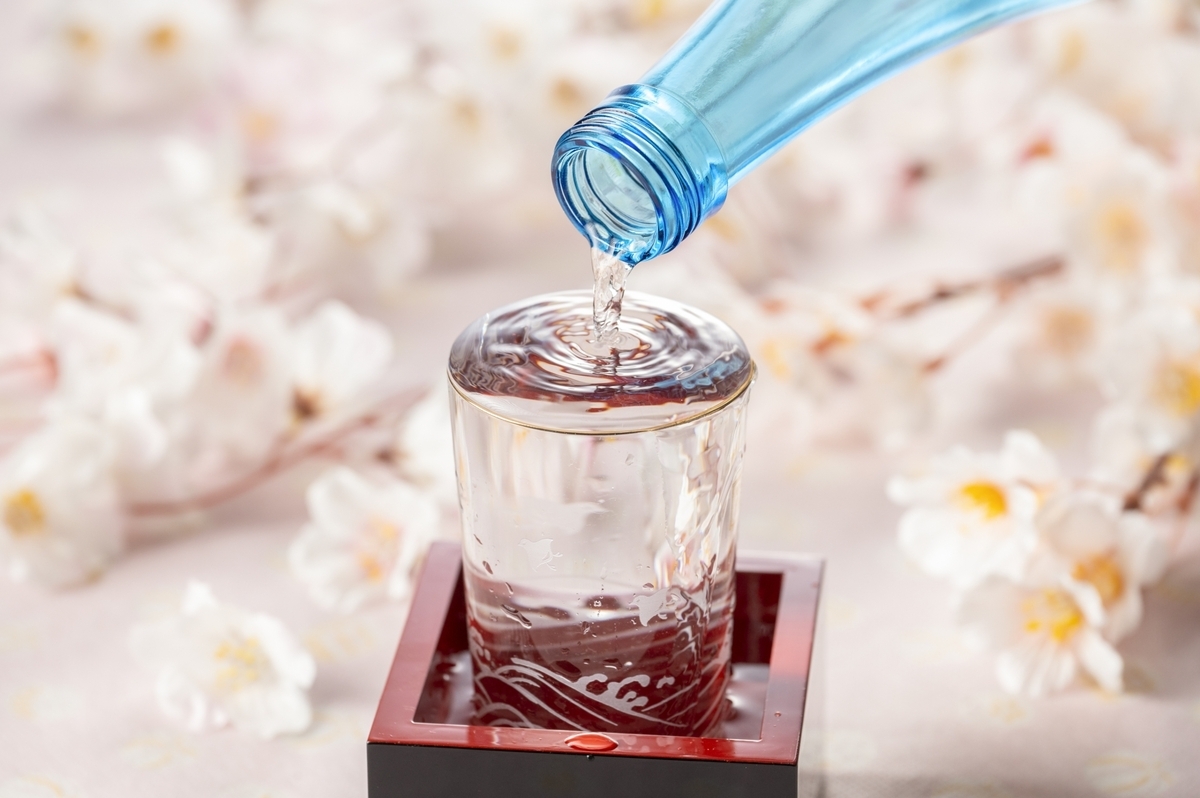 酒瓶から桝の上のガラス杯へ注がれる日本酒