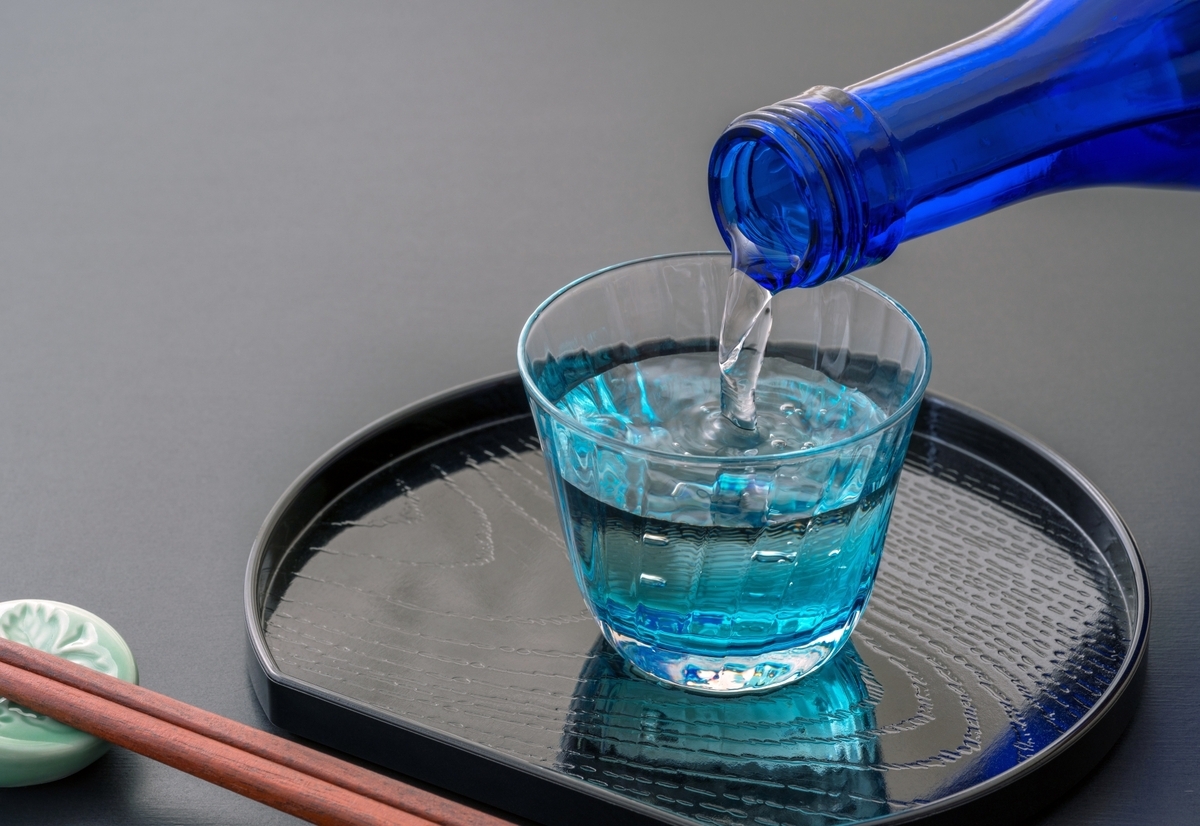 青いガラスのお猪口に冷酒を注ぐ様子