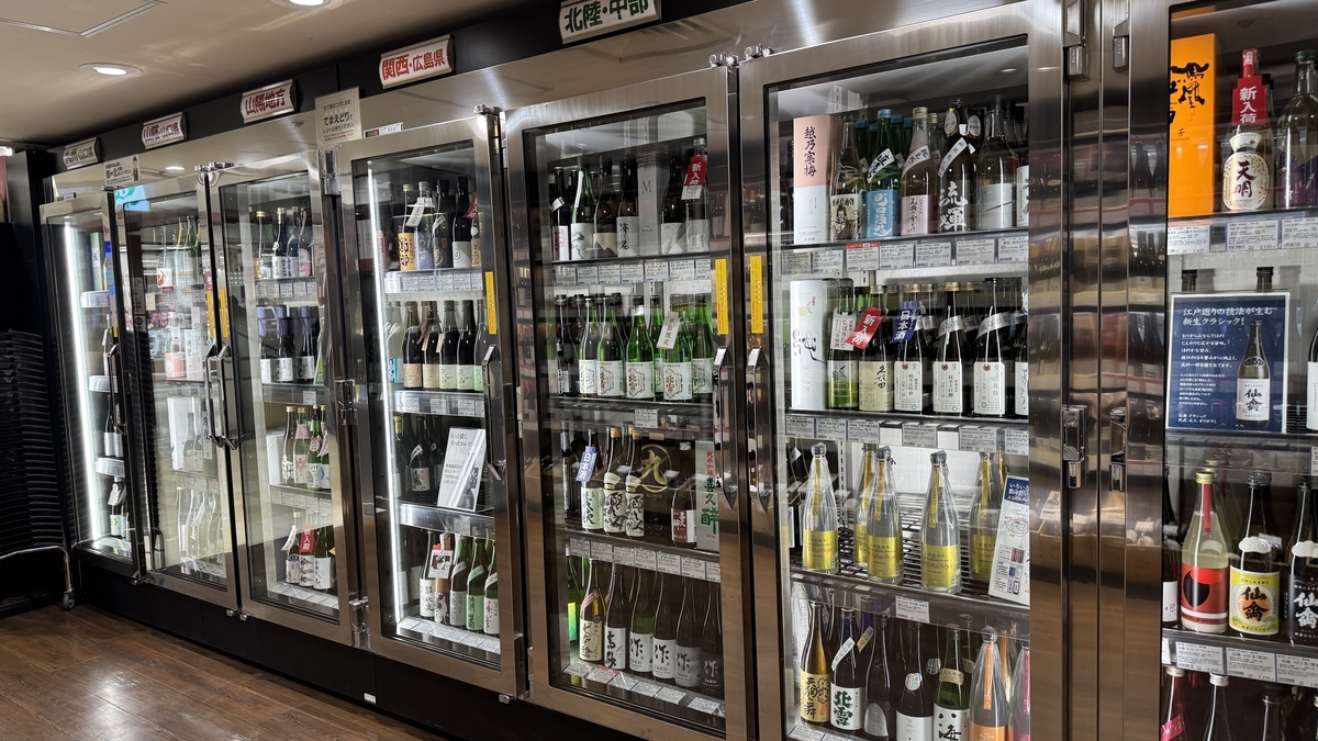 酒屋の冷蔵ショーケースに並ぶ日本酒の瓶とラベル