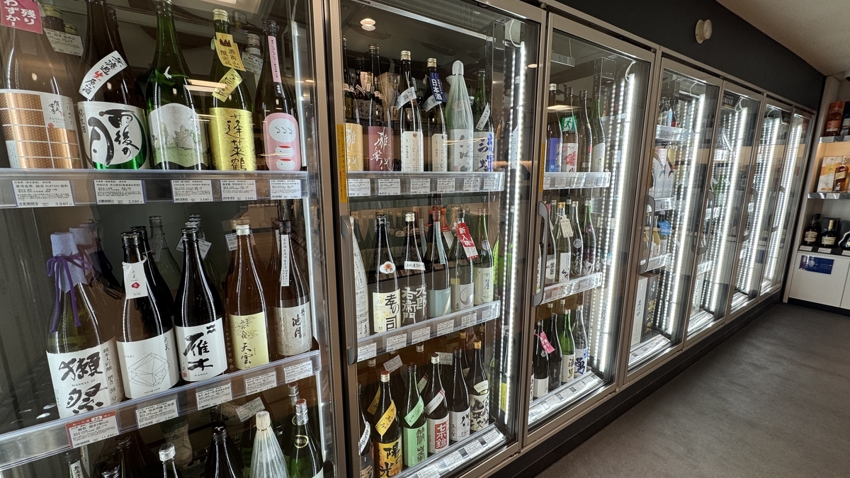 酒屋の冷蔵ショーケースに並ぶ多くの日本酒の瓶