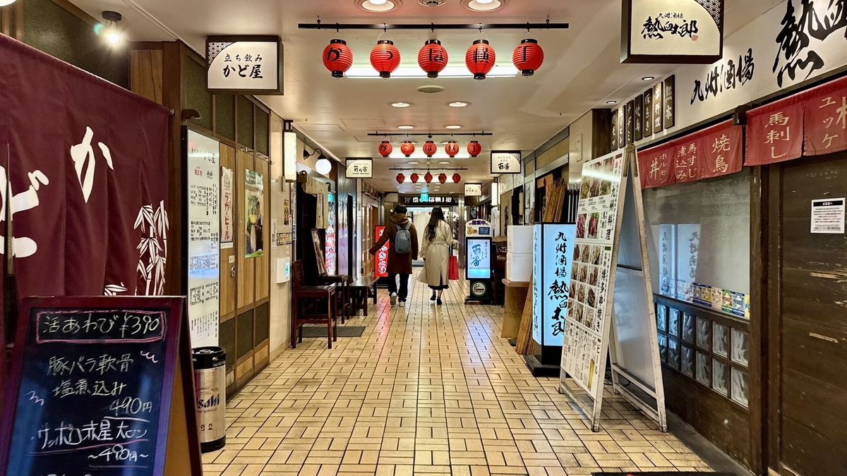 赤提灯が続く阪急かっぱ横丁のメイン通路を歩く来訪者と両側の飲食店