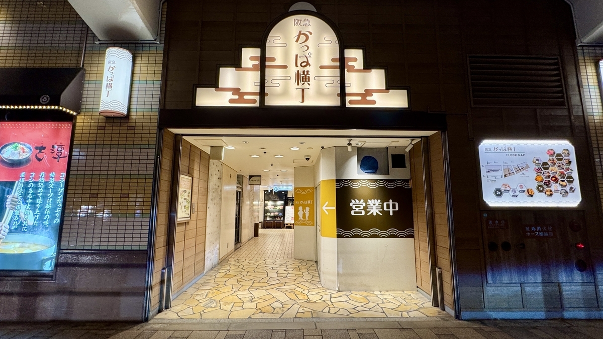 阪急かっぱ横丁の正面入口看板と営業中表示が見える高架下通路の入口