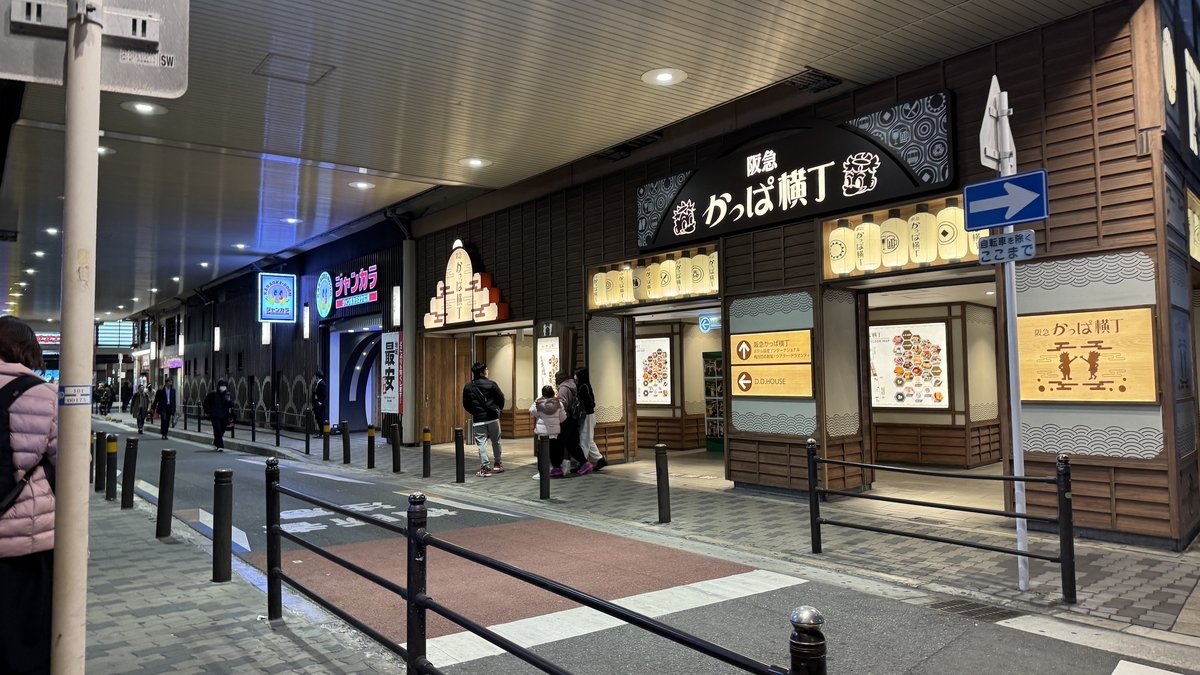 夜の車道沿いから見た阪急かっぱ横丁の外観と提灯が灯る複数の入口
