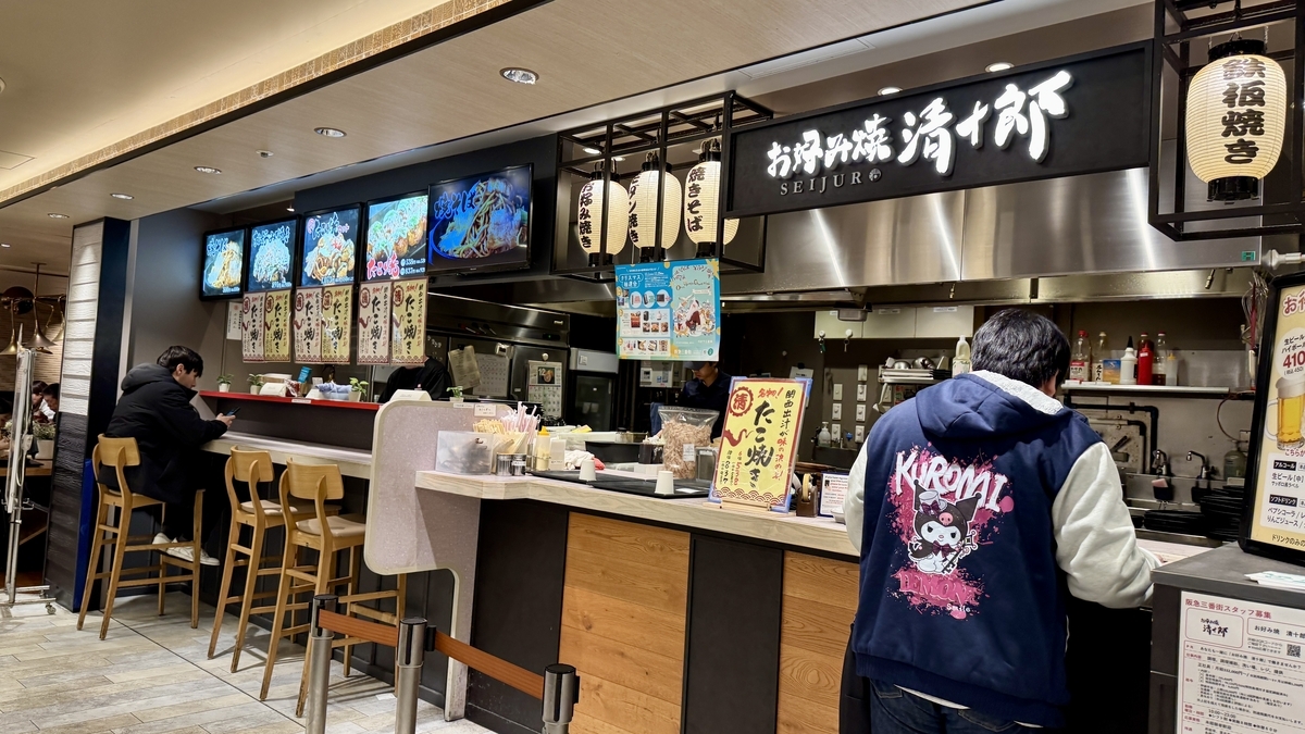 提灯と大きなメニュー看板が並ぶお好み焼清十郎のカウンター店舗外観