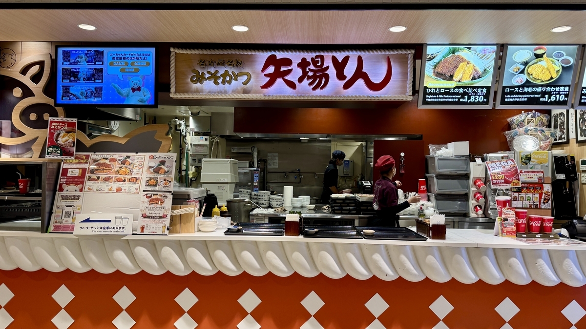 赤い暖簾と料理写真のディスプレーが目立つみそかつ矢場とんの店頭