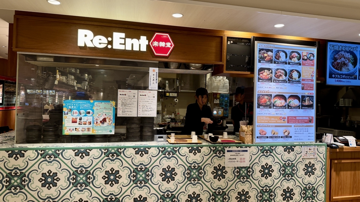 Re Ent楽韓堂のロゴ看板と石焼ビビンバの写真付きメニューが見える店頭