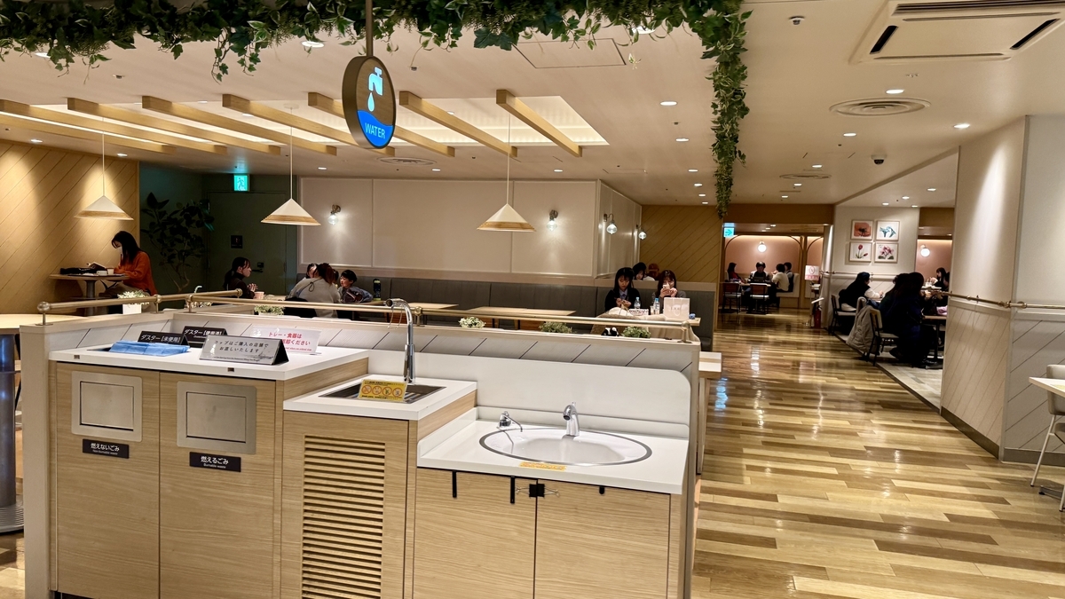 給水サインの下にゴミ分別箱と手洗い設備が配置されたセルフサービスコーナー