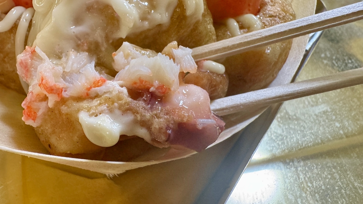 箸で割ったたこ焼きから見えるカニとタコ