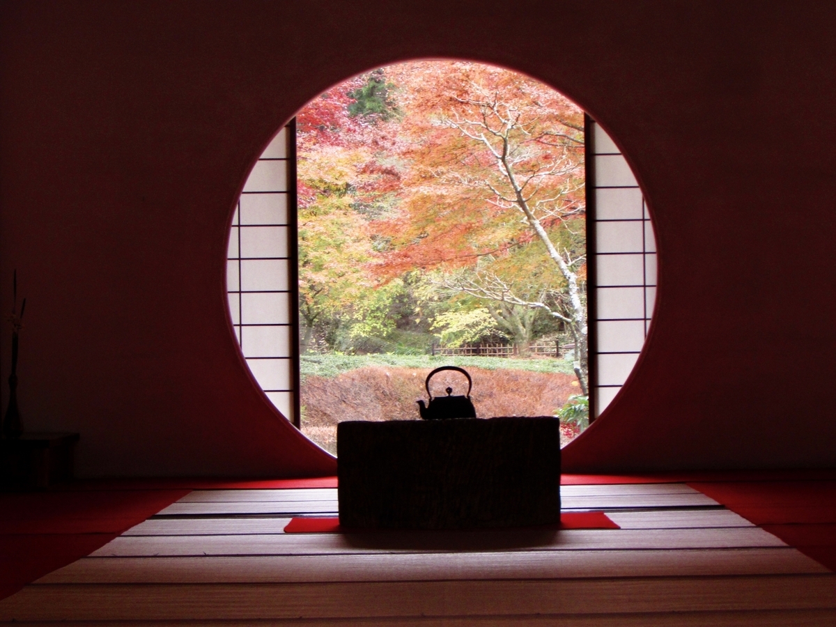 丸窓の向こうに紅葉が見える茶室