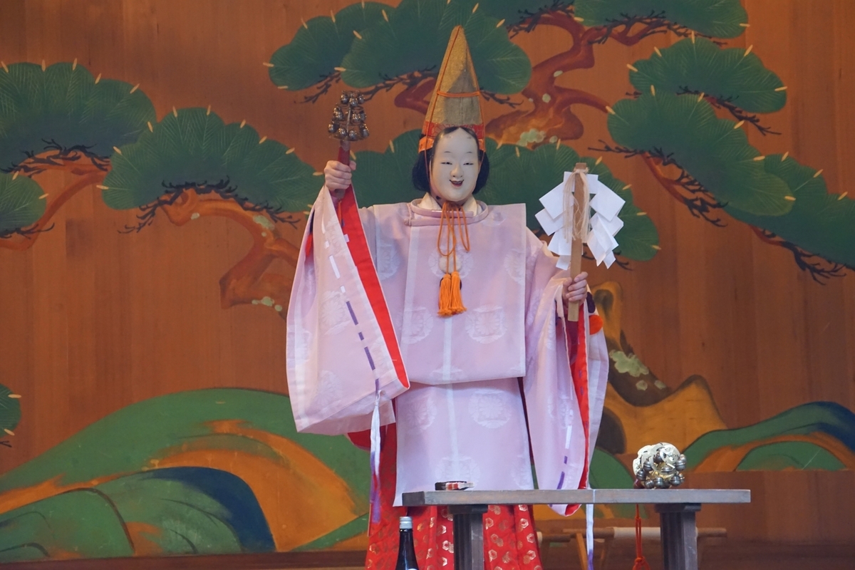 能面を付けた演者が舞台で舞う姿