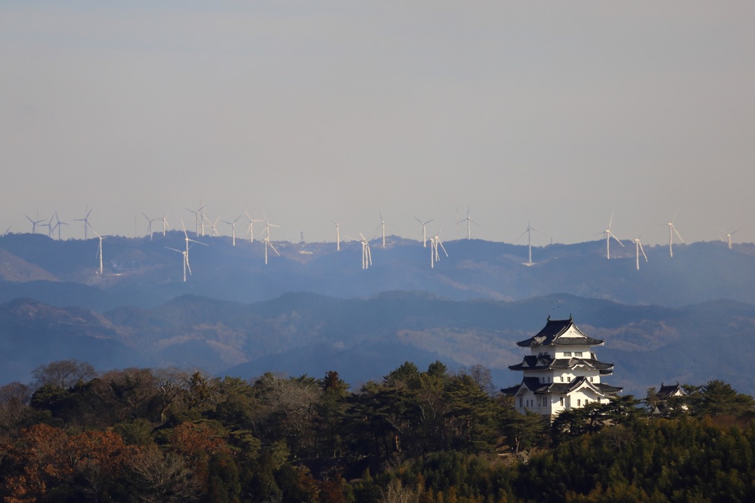 山並みと風車を背景に建つ白い城