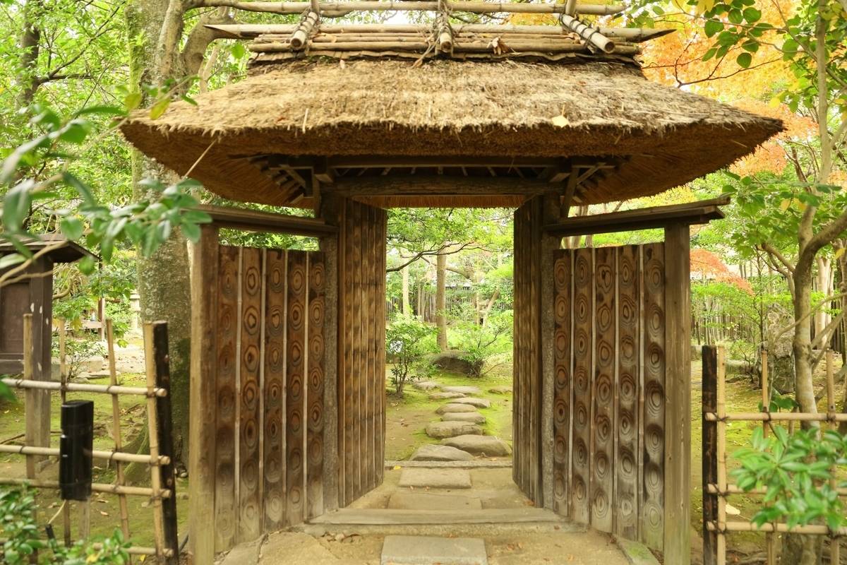 茅葺き屋根の木門と奥へ続く石畳の小道