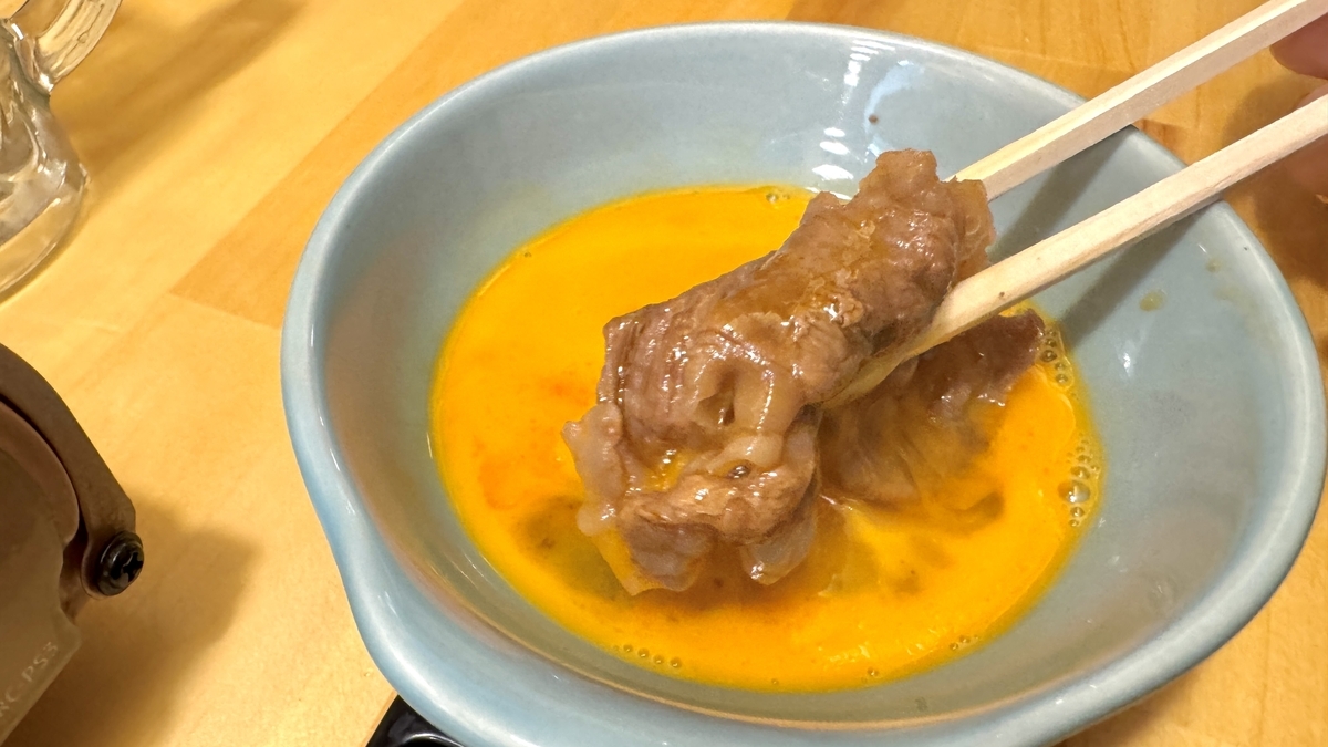 溶き卵にくぐらせたすき焼きの牛肉