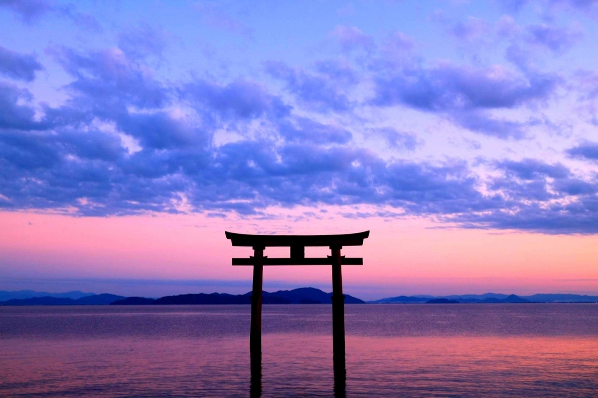 夕暮れの湖に立つ黒い鳥居