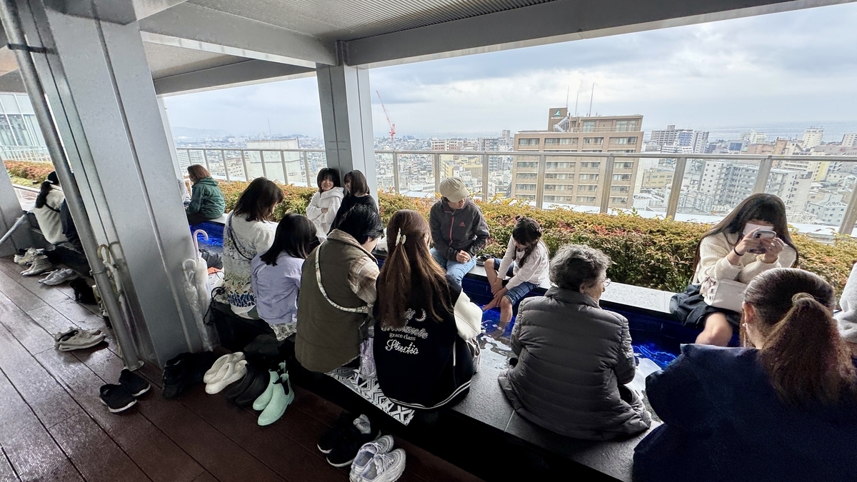 靴を脱いで足湯を楽しむ展望足湯庭園の利用者