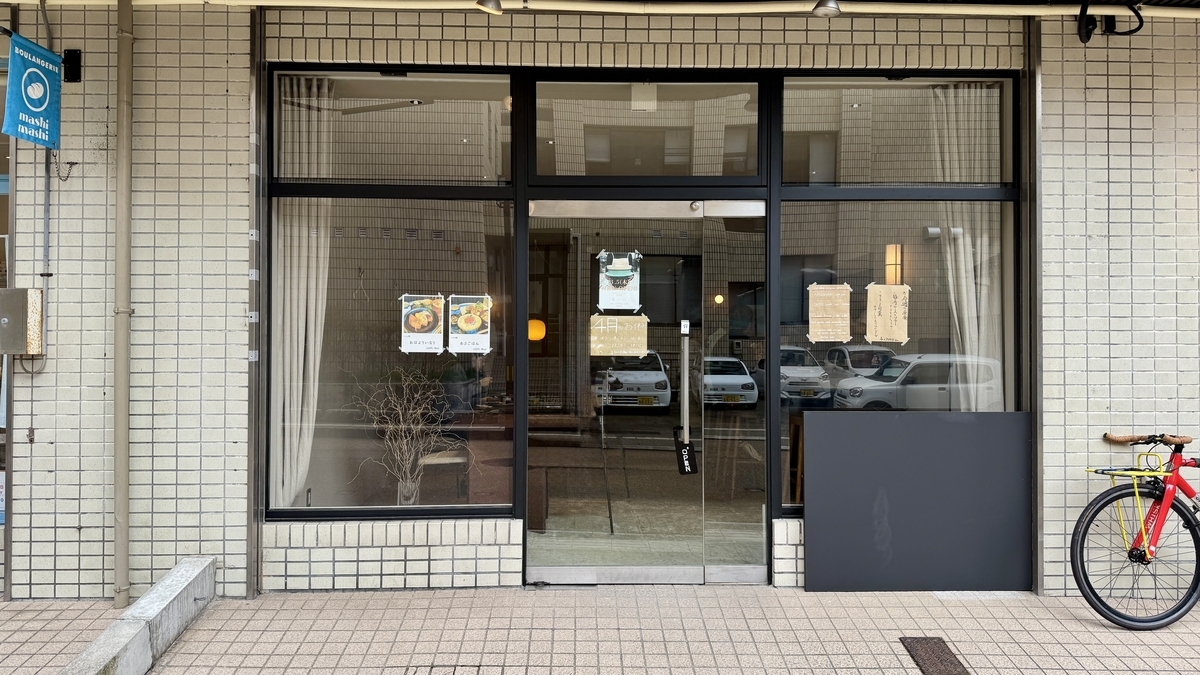 ガラス張りの入口があるこめじるしの外観