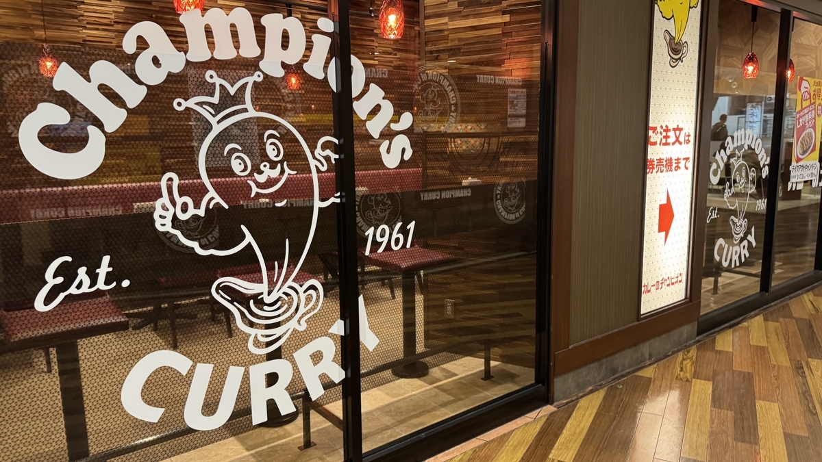 チャンピオンカレーのロゴと創業年が描かれた店頭ガラス