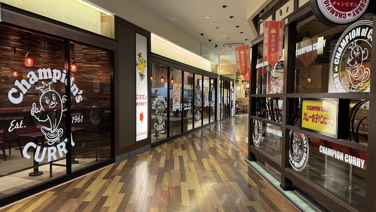 赤いのれんとロゴ入りガラスが続くチャンピオンカレー近江町店の店構え