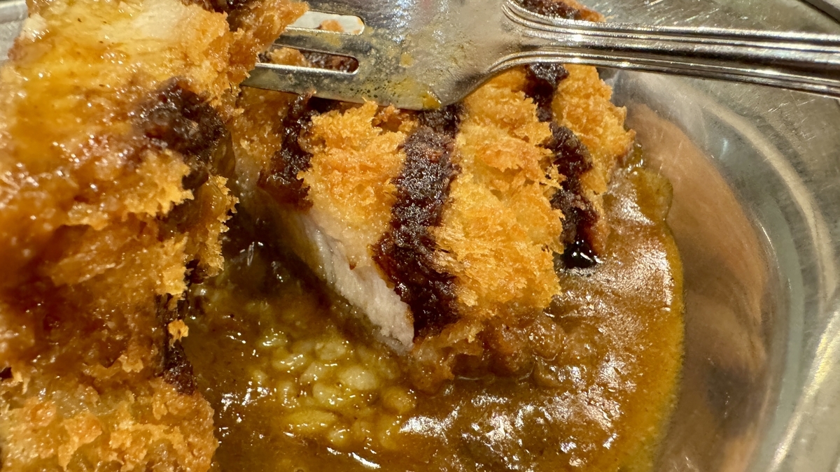 フォークで持ち上げた厚切りカツの断面とカレールー