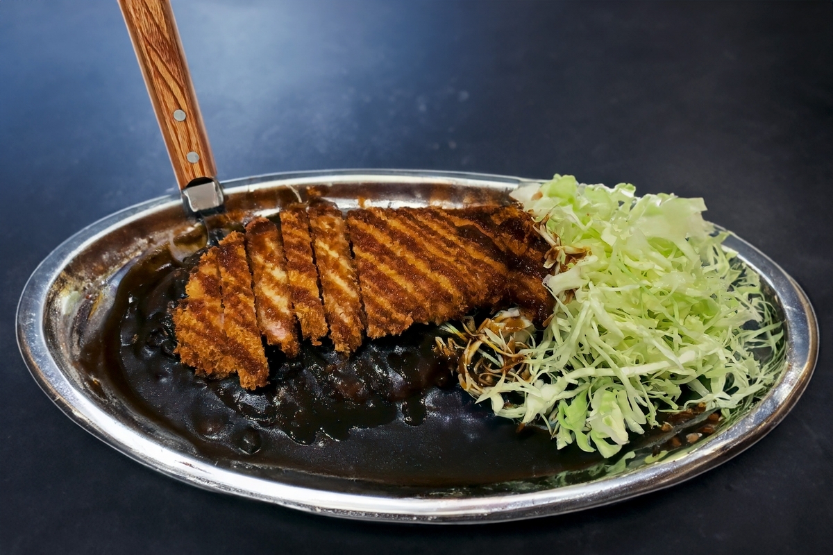 ステンレス皿に盛られたカツと千切りキャベツ付きの金沢カレー