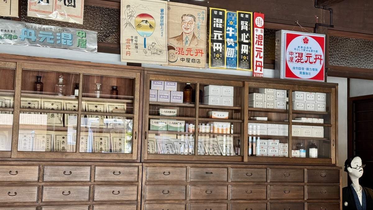 中屋薬舗の薬棚に並ぶ薬箱と昔の広告看板