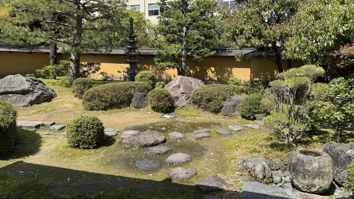 築地塀を背景に石灯籠と庭石が並ぶ日本庭園