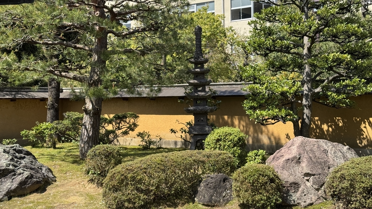 松と刈り込みの奥に立つ日本庭園の石灯籠
