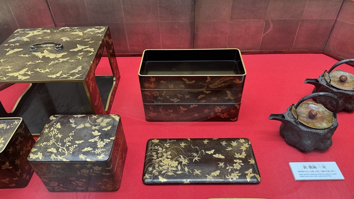 金蒔絵の重箱や文箱と鉄瓶が並ぶ展示