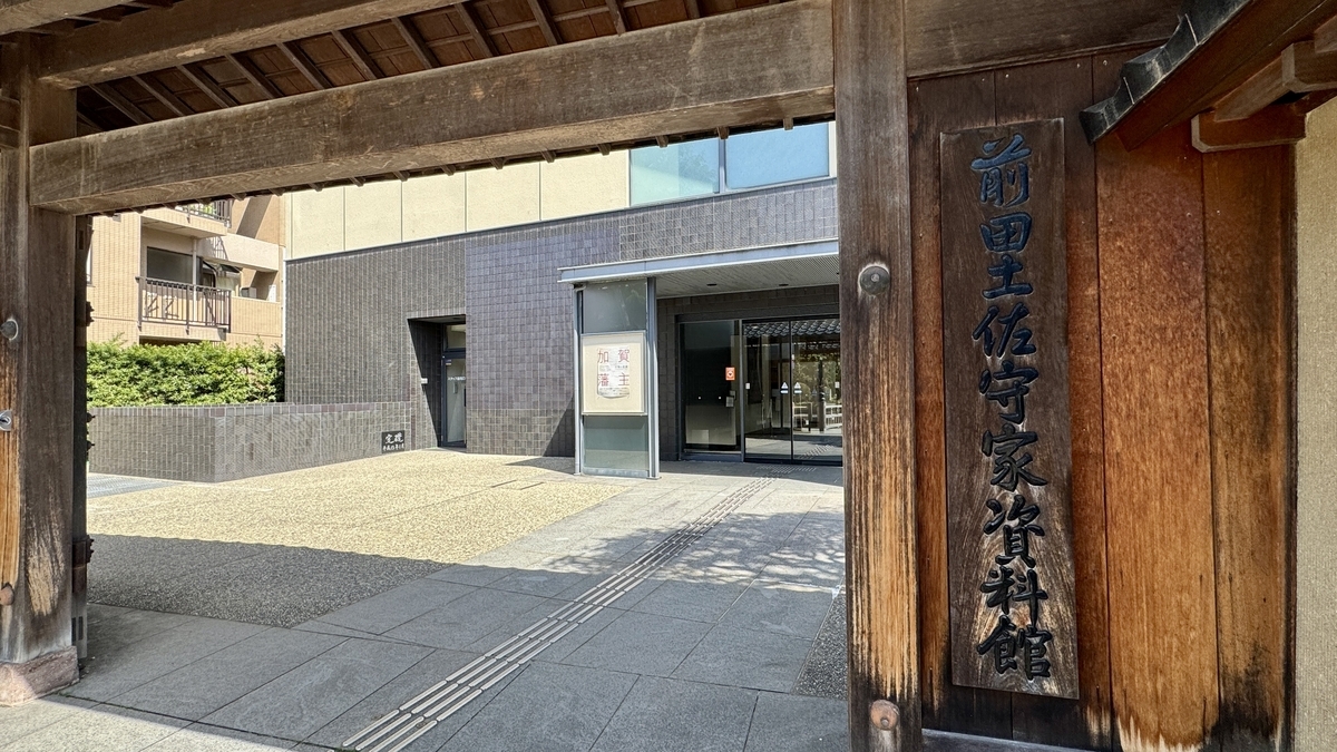 木門越しに見る前田土佐守家資料館の入口と木製看板